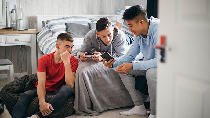 Szene zu Hause: Drei Jugendliche sind gemeinsam an ihren Smartphones.