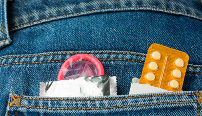 Foto: Nahaufnahme einer Hosentasche, darin stecken ein Kondom und Verhütungspille.