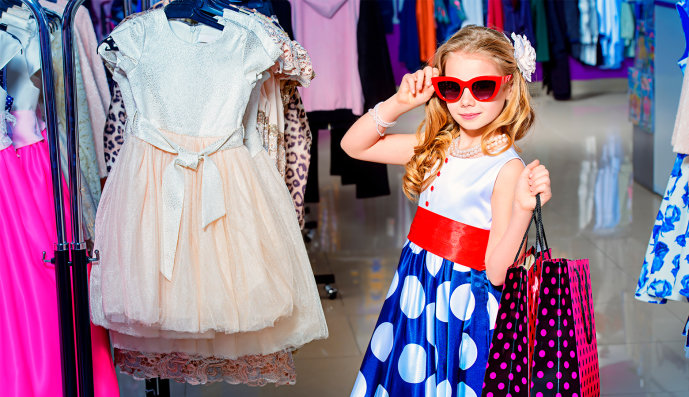 Foto: Kleines Mädchen mit Sonnenbrille und zwei Einkaufstüten in einer Boutique 