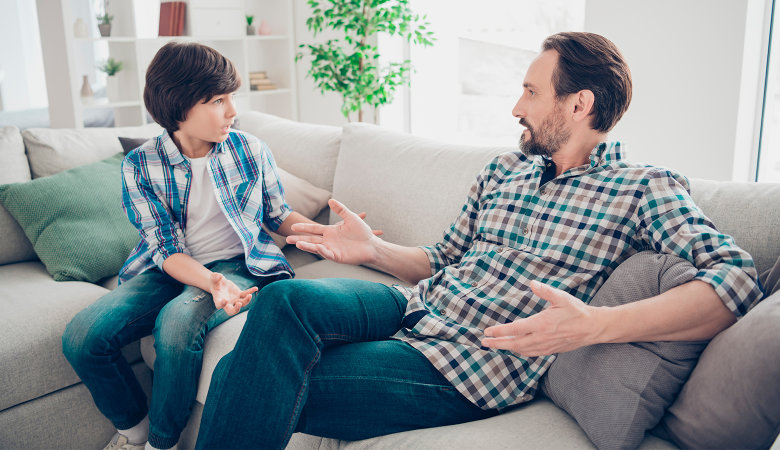 Foto: Vater und Sohn sitzen auf dem Sofa und diskutieren