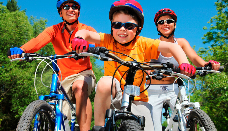 Foto: Vater, Mutter und kleiner Sohn sind mit Fahrradhelmen, Fahrradhandschuhen und Fahrrädern unterwegs