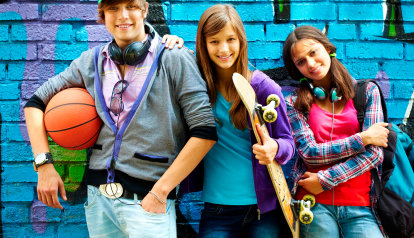 Foto: Drei Jugendliche Skateboarder lehnen an einer Ziegelwand.