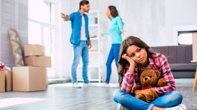 Foto: Trauriges Mädchen sitzt am Boden, da die Eltern streiten.