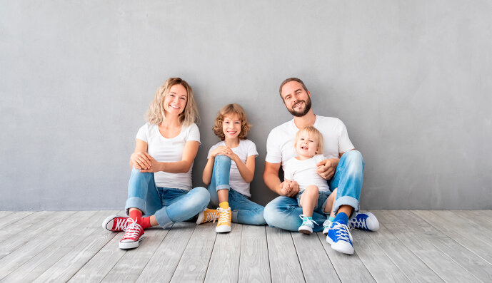 Foto: Fröhliche Familie mit zwei Kindern sitzen am Fußboden in ihrem neuen Zuhause.