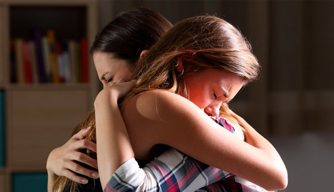 Foto: Zwei traurige Frauen halten sich umarmt.