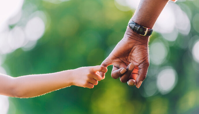 Foto: Die Hand einer afrikanischen Person hält die Hand eines Kindes.