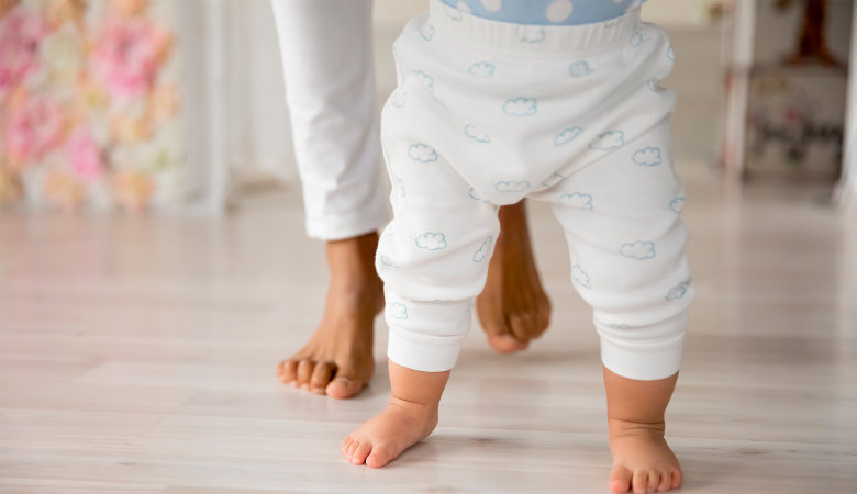 Foto: Die Füße eines Babys und seiner Mutter; Baby lernt das Laufen.