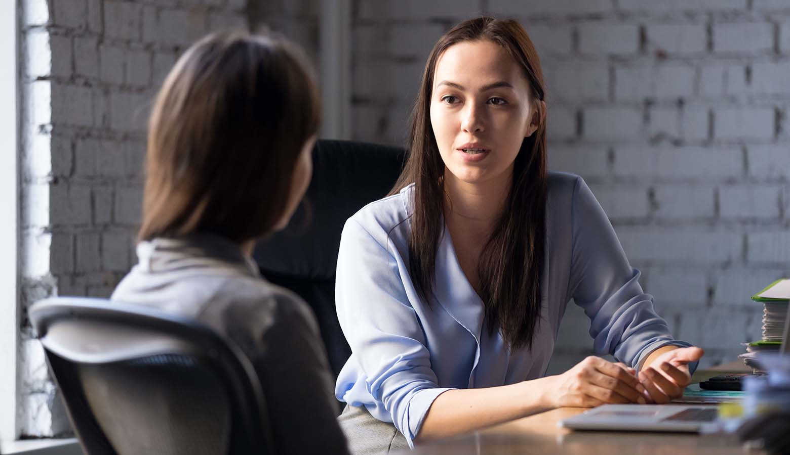 Zwei Frauen sitzen am Schreibtisch im Gespräch