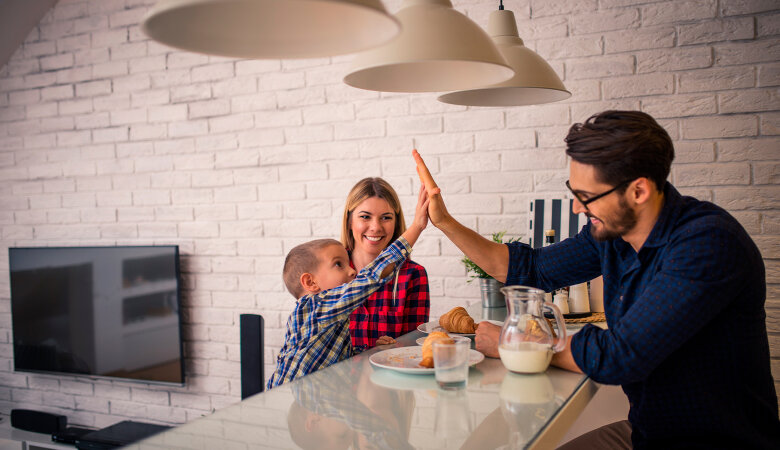 Foto: Mutter, Vater, kleiner Junge sitzen zusammen beim Frühstücken an einem Tisch