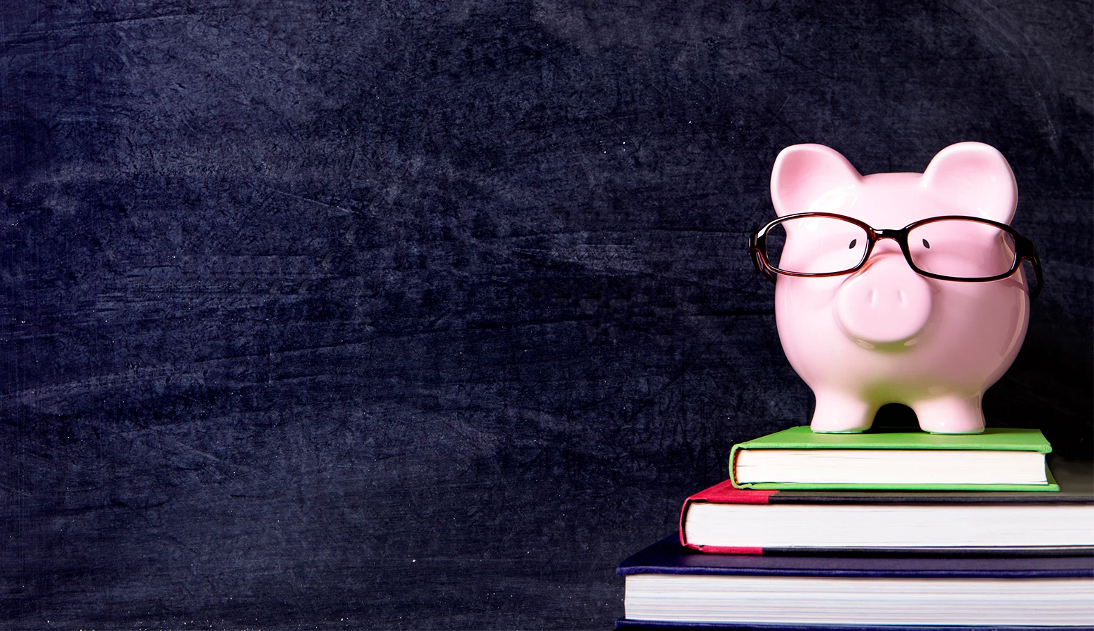 Foto: Keramik Sparschwein mit Brille steht auf drei Büchern