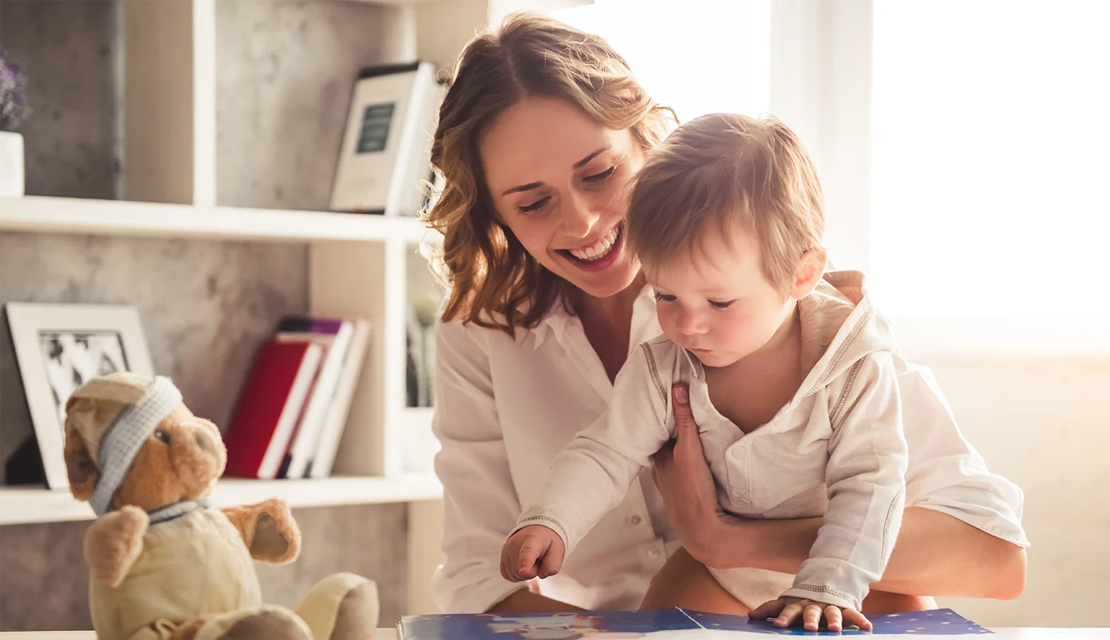 Mutter schaut mit ihrem Baby ein Bilderbuch an.