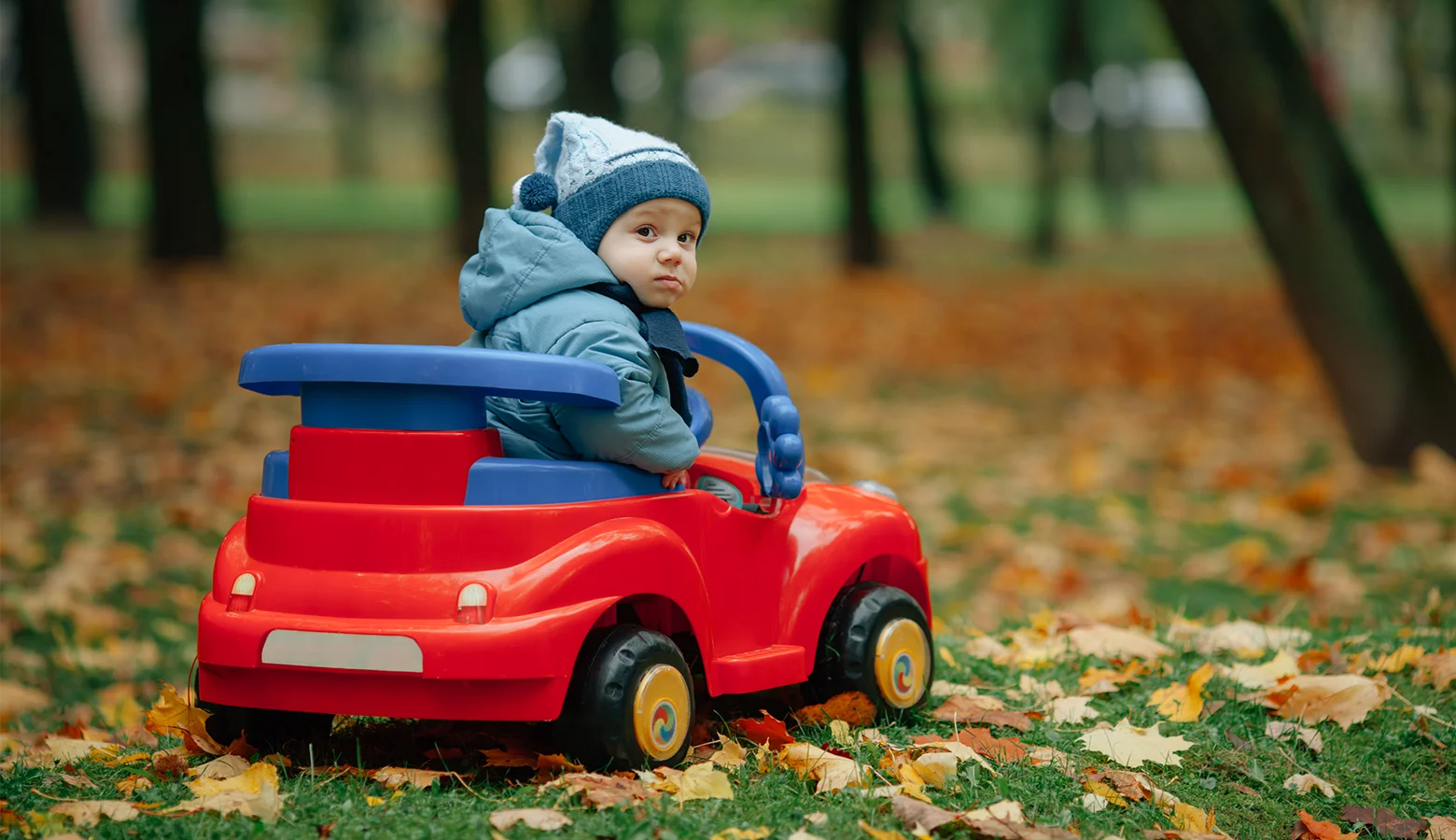 Kind sitzt in einem roten Kinderspielzeugauto