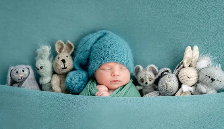 Ein schlafendes Baby liegt zwischen Kuscheltieren