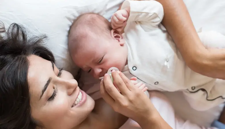 Mutter hält Baby mit Schnuller im Arm