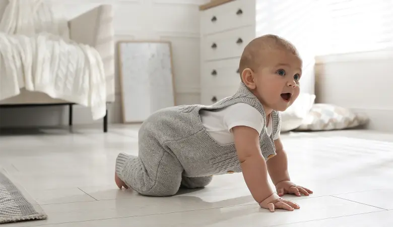 Baby krabbelt auf einem Teppich im Wohnzimmer.