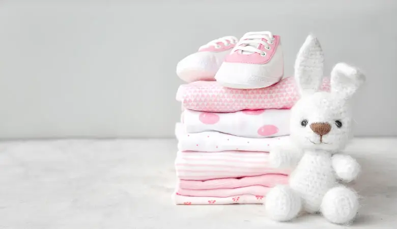 Babykleidung mit Babyschuhen und Teddybär