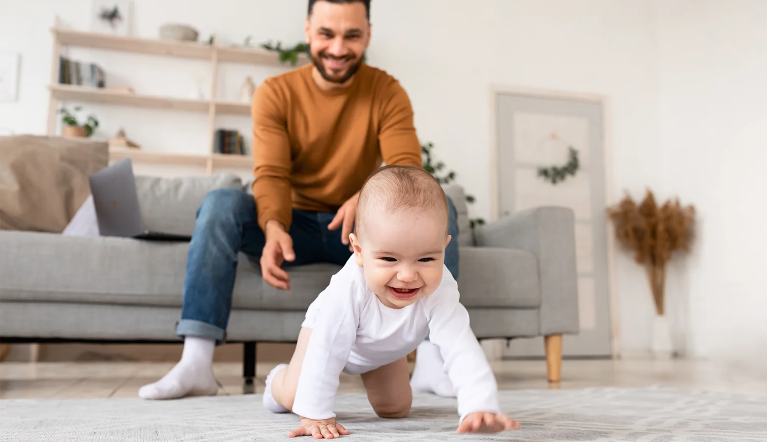 Papa sieht seinem Baby beim Krabbeln zu.