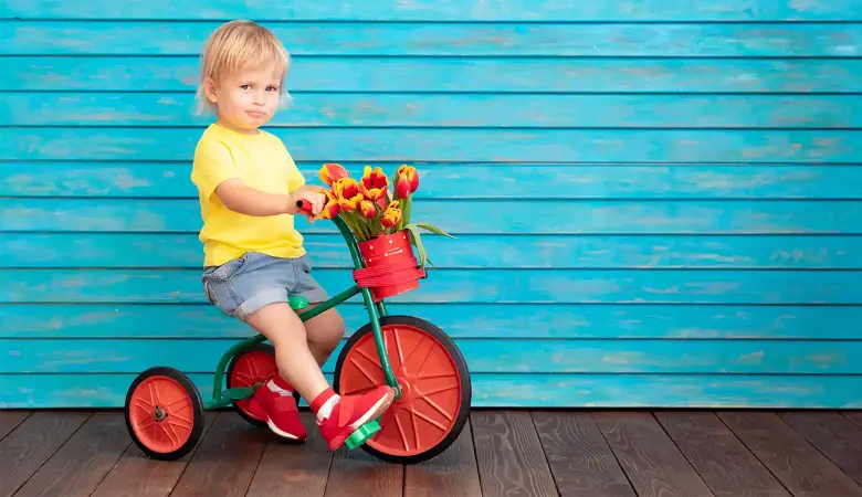 Kleiner Junge sitzt auf einem roten Kinderdreirad