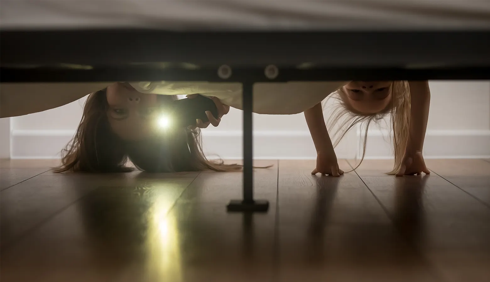 Zwei Kinder schauen unter das Bett