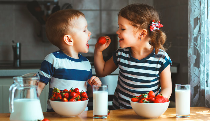 Foto: Zwei Kinder essen Erdbeeren und trinken Milch