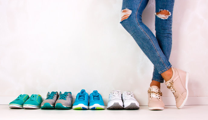 Foto: Mehrere Paar Sportschuhe und Beine eines Mädchen in Jeans.