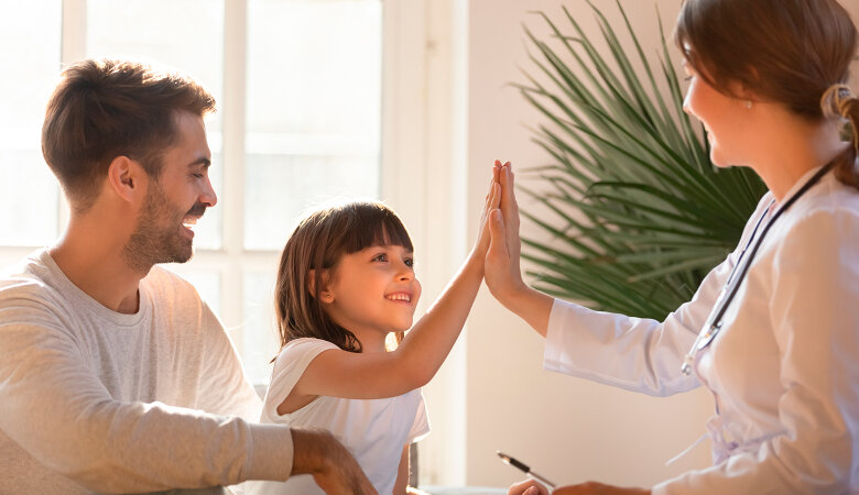 Foto: Fröhliches Kind mit Papa bei der Kinderärztin