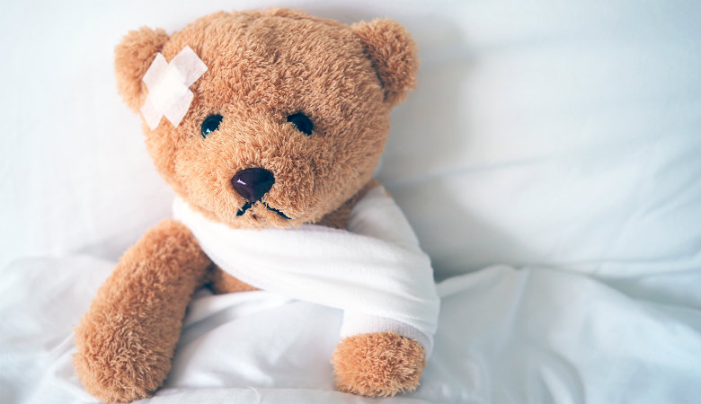 Foto: Teddybär mit Pflaster auf der Stirn und eingebundenen Arm