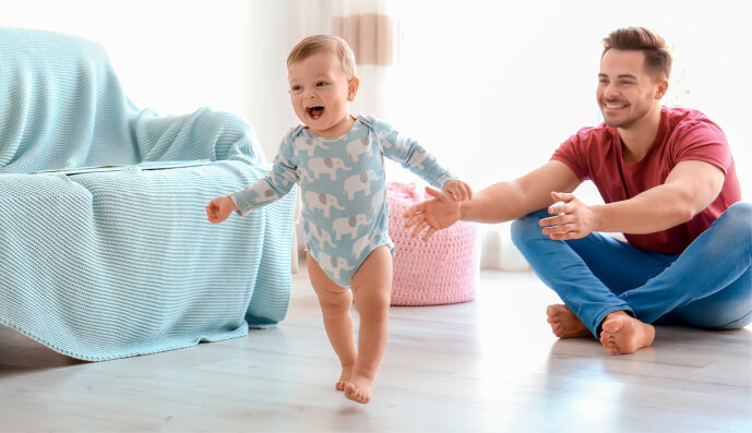 Foto: Baby macht die ersten Laufschritte mit der Hilfe des Vaters.