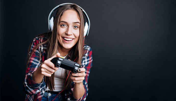 Foto: Fröhliches Teenager-Mädchen mit Kopfhörern auf hält einen Controller in der Hand