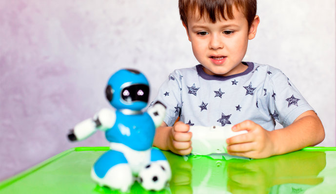 Foto: Kleiner Junge, der mit einem Roboter und einer Playstation spielt.