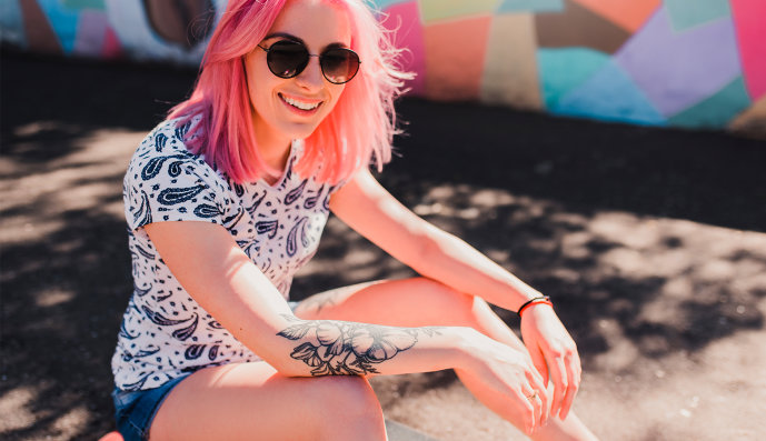 Foto: Junges Mädchen mit gefärbten Harren und Tattoos auf dem Arm.