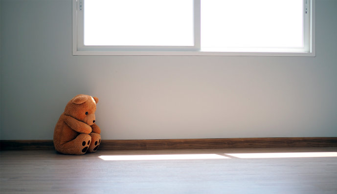 Foto: Teddybär sitzt unter einem Fenster auf dem Fußboden eines leeren Zimmers