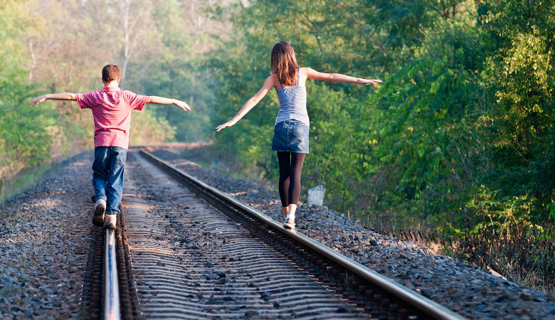 Foto: Zwei Grundschulkinder, die auf Bahnschienen balancieren.