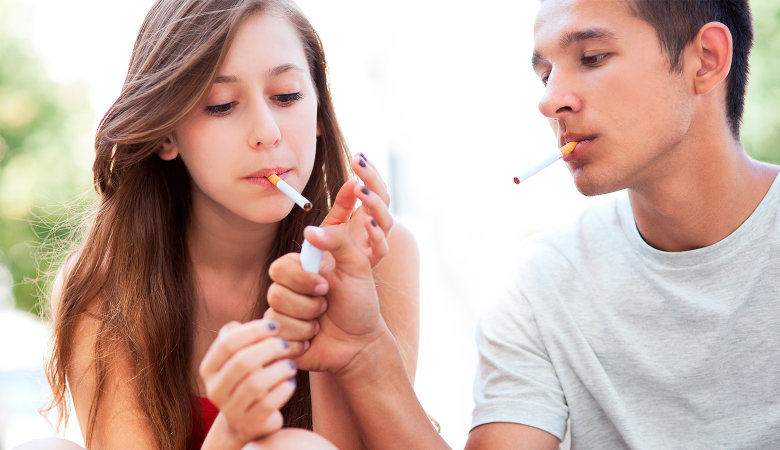 Foto: Junges Teenagerpaar die beide Zigaretten rauchen.