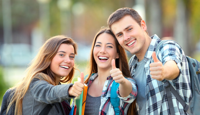 Foto: Zwei lachende Schülerinnen und ein lachender Schüler mit Daumen nach oben
